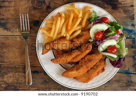 Golden deep fried chicken finger dinner on wood background
