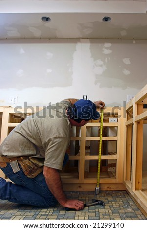 Finish carpenter working on custom home cabinets in home kitchen