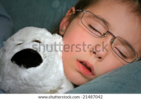 Sleeping child with stuffed animal on couch.