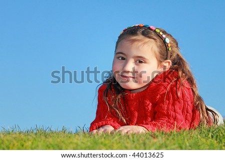 Child laying on grass outside.