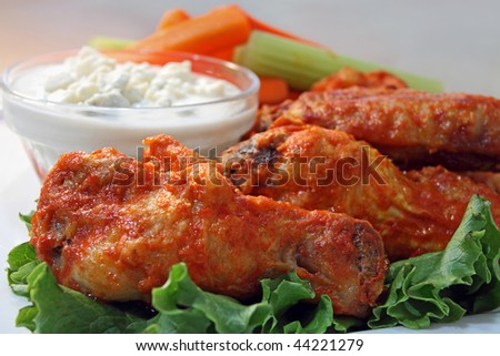Hot wings on plate with chunky blue cheese dipping sauce.