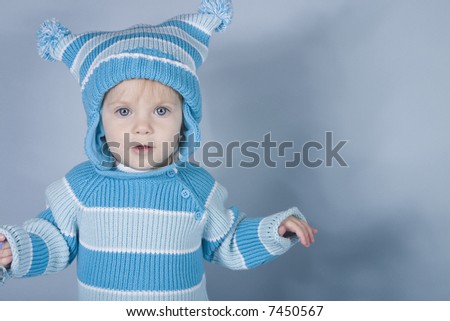 A cute baby in a striped hat and sweater