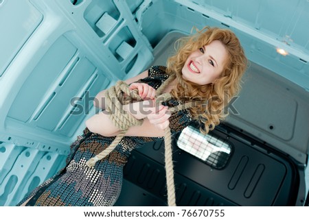 Pretty young woman in ropes in cargo van inside