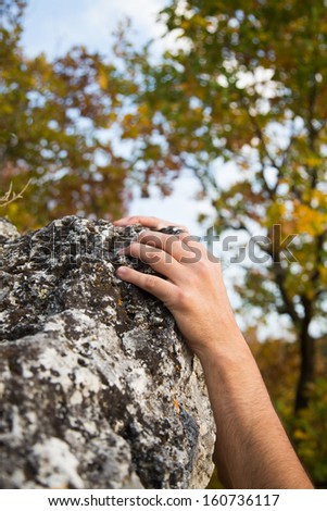 Rock climber\'s hand grasping handhold on natural cliff.