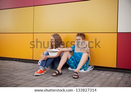 Homeless teenage boy and girl begging in street (The production scene; problem-free children play a role of beggars)