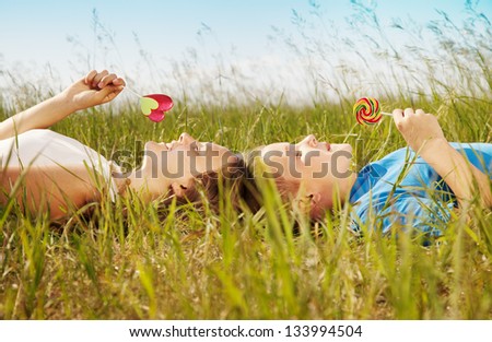 Children lie on a grass and eat sweet sugar candies