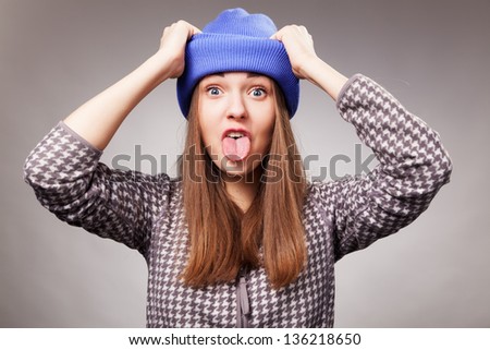 young girl makes funny face in closeup over grey background