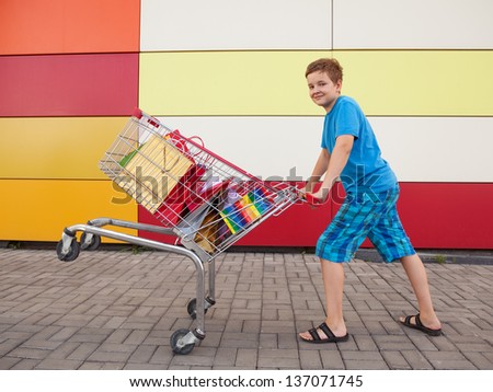 boy with shopping trolley full of purchases in the street