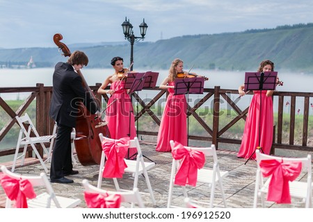 Quartet of classical musicians playing at a wedding outdoors near the river