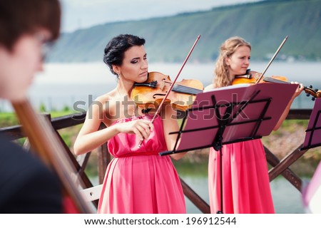 Girls plays violin outdoors near the river