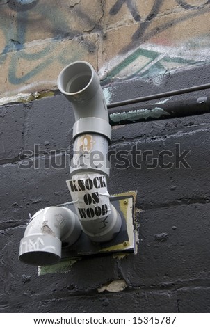 Back alley vent pipes with graffiti and sticker.