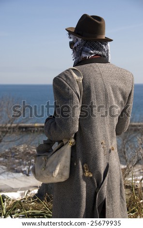 Stock photo of the back of a traveling man - hobo - his coat is covered in burrs