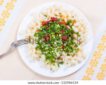 Pasta with tomato sause, meat, spring onion on white dish. As decoration linen table-cloth.
