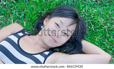 Cute asian woman laying down on green lawn