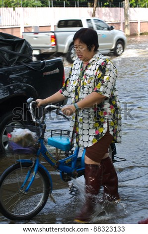 BANGKOK, THAILAND-NOVEMBER 7: An unidentified women and hand bicycle in a flooded street during the worst flooding in decades  on November 7, 2011  Nuan Chan Road, bangkok, Thailand.