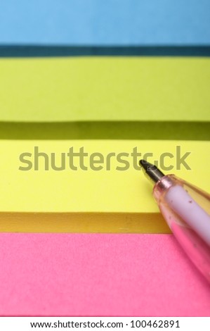 Pink pen and yellow, green, blue, pink, pieces of paper for notes
