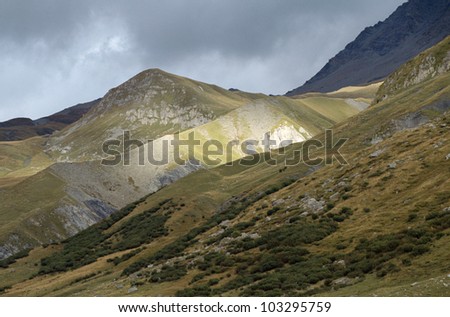 Savoy mountains and pastures in Tarentaise, France and stormy sky with light ray. France