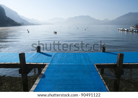 Blue pontoon forming a cross on lake annecy on morning, France