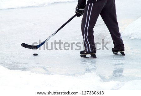 man with ice skates and stick on winter ice play hockey