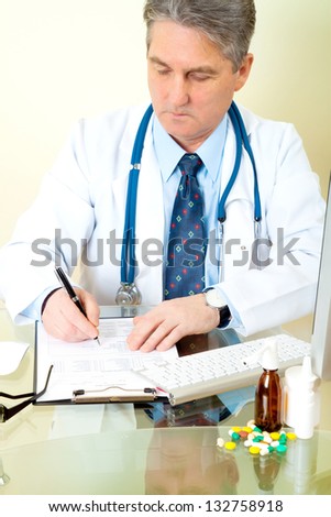 Doctor on his workplace with computer, pills, tablets, write a prescription patient data history