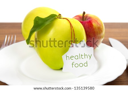 dieting and health food. Yellow, green apple with leaf and white sticker on plate