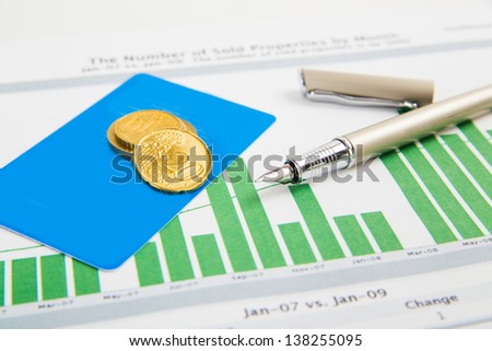 coin, a pen and business card on the business papers