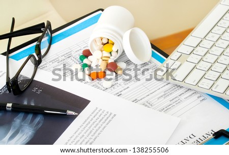 Doctor workplace. Pills, tablets, pen on patient history database