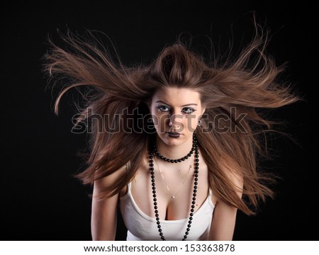 Beautiful brunette girl with studio fan wind on black background