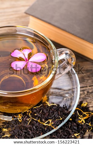 Glass Cup Tea with pink flower and Mint Leaf, on brown wooden palette