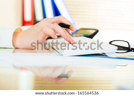 Woman with beautiful hands working on the calculator and keyboard in business office