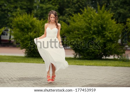 Alluring brown-haired woman outdoors in luxury elegant dress. Romantic girl in a white sundress walking in the park. romantic concept