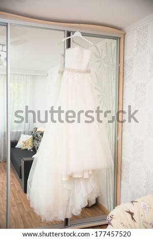 wedding dress hanging on mirror at hotel room