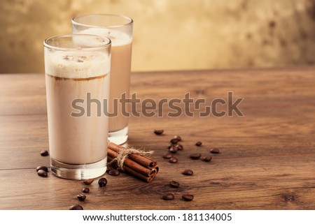 Full glass of milk cocktail and coffee beans on the wooden background