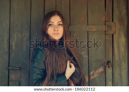 Sexy gorgeous young woman with long hair near old wooden wall