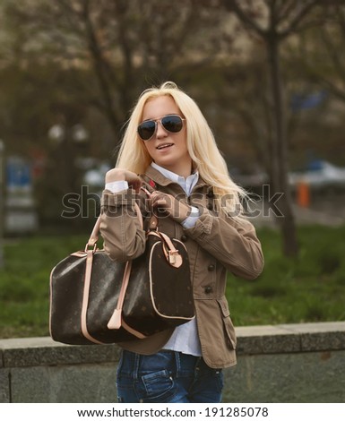 Beautiful blonde woman in sunglasses wearing loose dress in city. Brown color toning photo