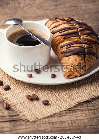 Cappuccino and croissant on wooden table