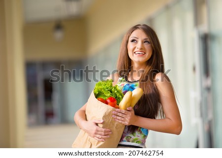 stunning and very beautiful woman in dress with long brown hair holding food in bag near shop