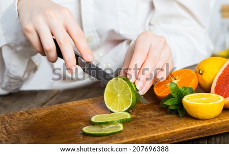 young clean chef hands cutting green lime on old wooden table in kitchen