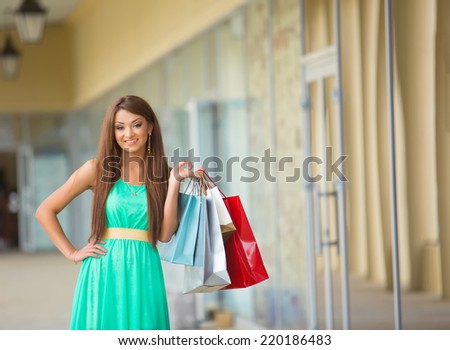 stunning and very beautiful woman in dress with long brown hair with colored shopping bags