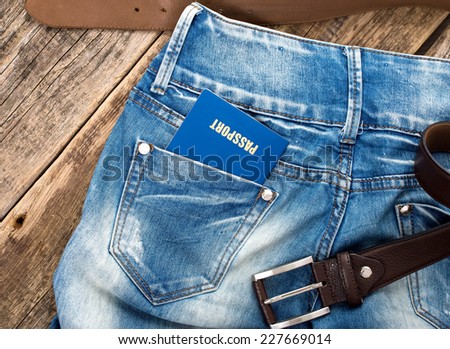 Man standing with American blue passport in back pocket of denim blue jeans with copy space.