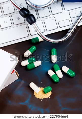 close-up green, white open medical capsules, (one opened), on black background