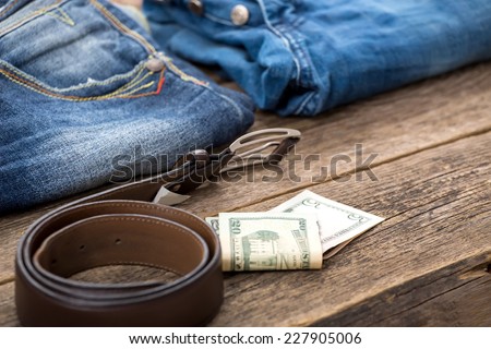 Dirty jeans, money and belt on wooden floor