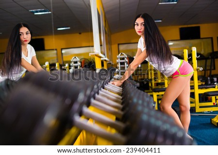 brunette sexy fitness girl in sport wear with perfect body in the gym posing
