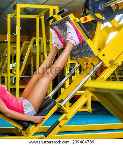 Side view of a fit young woman doing leg presses in the gym