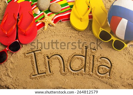 Summer concept of sandy beach, colorful thongs shoes, sunglasses, ball and inscription