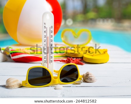 Summer concept of high temperature, flip flop shoes, sunglasses on pier near hotel pool