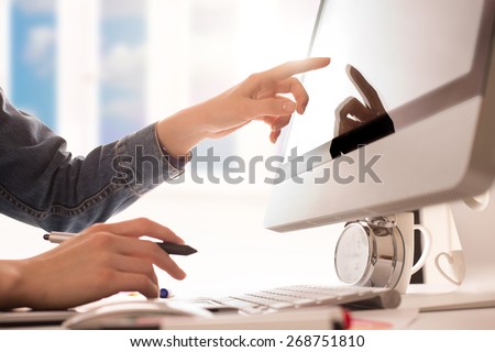 young woman artist in jeans jacket drawing something on graphic tablet and touchscreen at the office