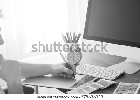 Young Handsome Graphic designer using graphic tablet to do his work at desk black and white