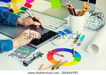 Young Handsome Graphic designer using graphics tablet to do his work at desk