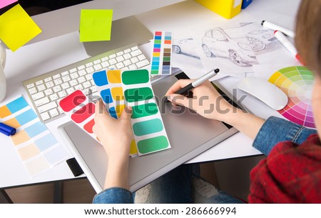 Young pretty Graphic designer using graphics tablet to do her work at desk